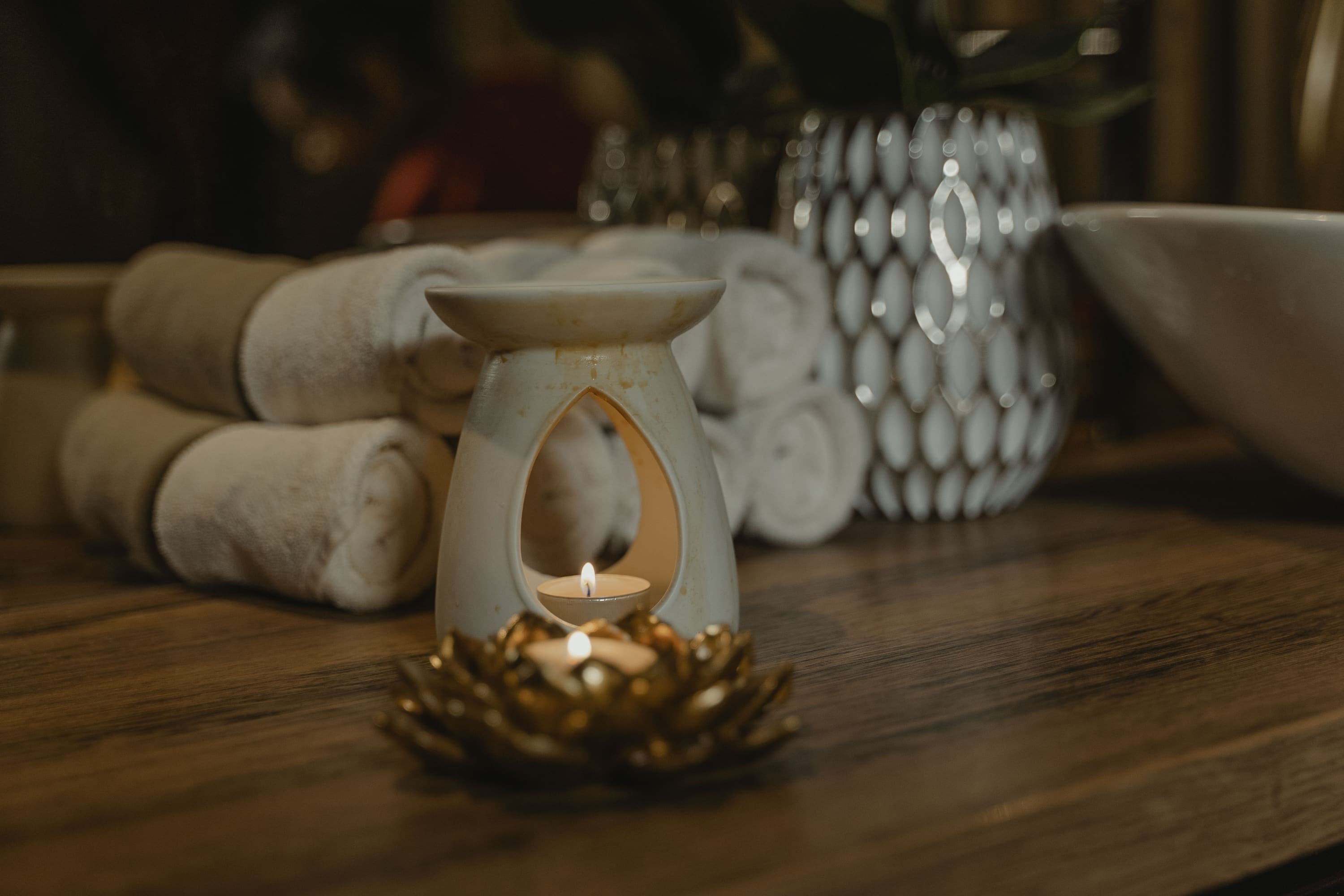 Aroma burner lit beside rolled towels
